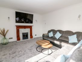 A living room with a sofa, coffee table, and fireplace at Tymelyn in Aberystwyth