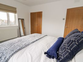A bedroom with a bed and mirror at Tymelyn in Aberystwyth