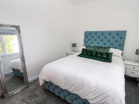 A bedroom with a bed and mirror at Tymelyn in Aberystwyth