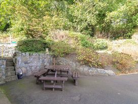 A garden with a wooden table and benches at Tymelyn in Aberystwyth