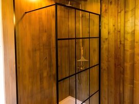 A shower enclosure with water controls and wood paneling at Badger - Luxury Glamping Retreat in Battle
