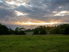 A field with trees and clouds during sunset at Badger - Luxury Glamping Retreat in Battle