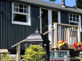 A cabin with windows, plants, and flowers at Tylands in Camelford