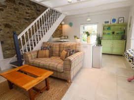 A living room with a sofa and kitchen counter at Cubs Corner in St Agnes