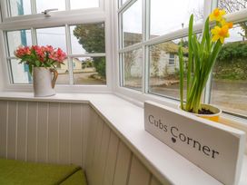 A sunroom with flowers and a sign at Cubs Corner in St Agnes