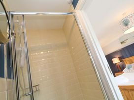 A shower area with tiled walls and a doorway at Cubs Corner in St Agnes