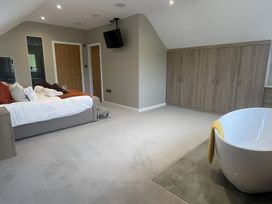 A bedroom with a bed, towels, wardrobe, and a bathtub at Pendle View Preston