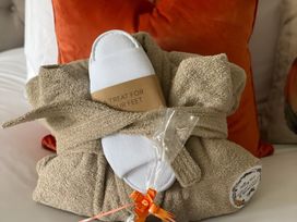 A bathrobe and slippers arranged as a gift in a bedroom at Pendle View Preston