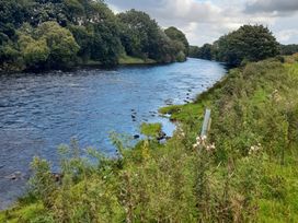 A river bordered by trees and grass in a natural setting at The Farmhouse in Omagh