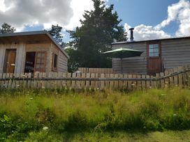 A cabin with a fence and umbrella at Bryn Mawr Cabin in Craven Arms