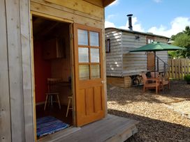 An outdoor seating area with a table and chairs near a wooden building at Bryn Mawr Cabin in Craven Arms