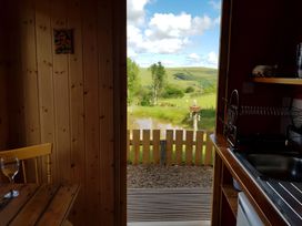 A kitchen with a view of the landscape and water at Bryn Mawr Cabin in Craven Arms