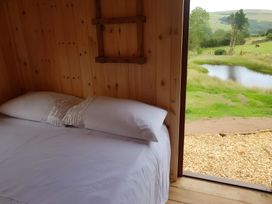 A bedroom with a bed and a view of a pond at Bryn Mawr Cabin in Craven Arms