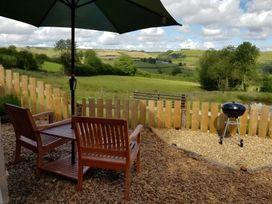 An outdoor seating area with furniture and a grill at Bryn Mawr Cabin in Craven Arms