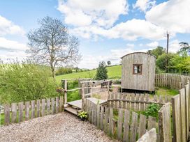 A fenced area with a wooden hut and table at Bryn Mawr Cabin Clun