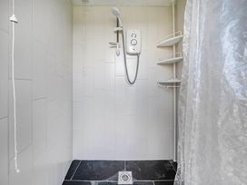 A shower with wall tiles and drain at Bryn Mawr Cabin in Clun