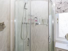 A shower with glass doors and a mirror at Beechtree Lodge 46 in Denny