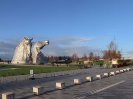 Two horse sculptures in a park with people walking at Beechtree Lodge 54 Denny