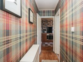 A hallway with plaid wallpaper and a view into a kitchen area at Beechtree Lodge 56 Denny