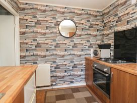 A kitchen with a gas stove and microwave at Beechtree Lodge 57 in Denny