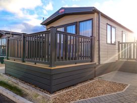 A cabin with a deck and railing at Paws By The Sea in Norwich