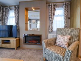 A living room with a television and armchair at Paws By The Sea in Norwich