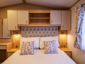 A bedroom with a bed and wall cabinets at Paws By The Sea in Norwich