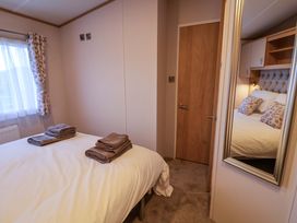 A bedroom with two beds and towels arranged at Paws By The Sea in Norwich
