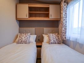 A bedroom with two single beds and a shelf at Paws By The Sea Norwich