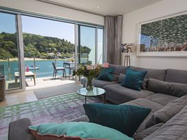 A living room with a sofa, coffee table, and a view of the water at Villa 8, Estura in Salcombe