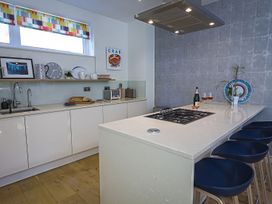 A kitchen with a stove and bar stools at Villa 8, Estura in Salcombe