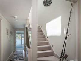 A hallway with a staircase and fishing rod at Villa 8, Estura Salcombe
