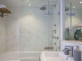 A bathroom featuring a shower, bathtub, sink, and green decorative vase at Villa 8, Estura in Salcombe