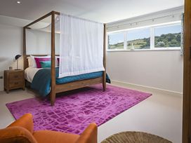 A bedroom with a four-poster bed and windows at Villa 8, Estura in Salcombe