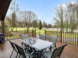 A deck with a table and chairs overlooking a grassy area at Cabin 1 Moffat Manor in Beaufort