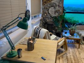 A room with a desk, lamp, chair, plants, and books at The Retreat Cabin in Llanelli