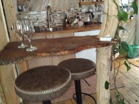 A kitchen with a bar table and stools at The Retreat Cabin in Llanelli