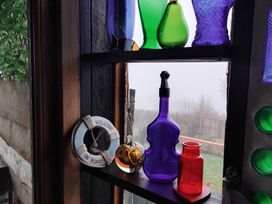 A collection of colorful bottles and a welcome sign on a window at The Retreat Cabin in Llanelli