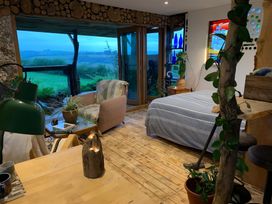 A bedroom with a bed and chairs at The Retreat Cabin Llanelli