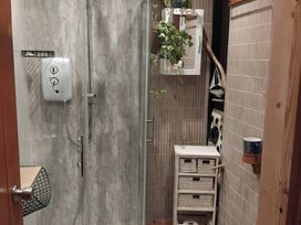 A shower with wall panels and storage basket at The Retreat Cabin in Llanelli
