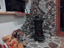 A living room featuring a wood stove and stone wall at The Retreat Cabin in Llanelli