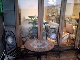 An outdoor seating area with a table and chairs looking into a room with a bed at The Retreat Cabin in Llanelli