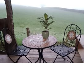 A table with two chairs and glasses on a patio at The Retreat Cabin in Llanelli