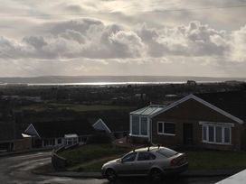 A view of houses and a car with a cloudy sky in the background at The Retreat Cabin in Llanelli