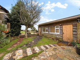 An outdoor view of a cabin with a tree and pathway at The Retreat Cabin in Llanelli