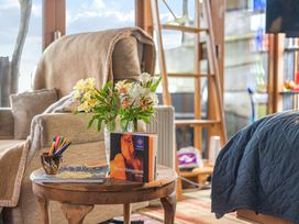 A living room with a flower vase and books on a table at The Retreat Cabin in Llanelli