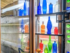 A display of colorful glass bottles in a window at The Retreat Cabin in Llanelli