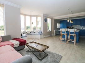 A living room with a blue kitchen and seating at Cootiya Corner in Great Lyth
