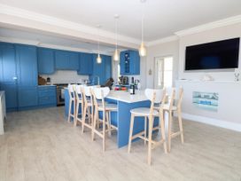 A kitchen with blue cabinets and an island with bar stools at Cootiya Corner in Great Lyth