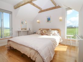 A bedroom with a bed and a mirror at Seren Fach in Pwllheli